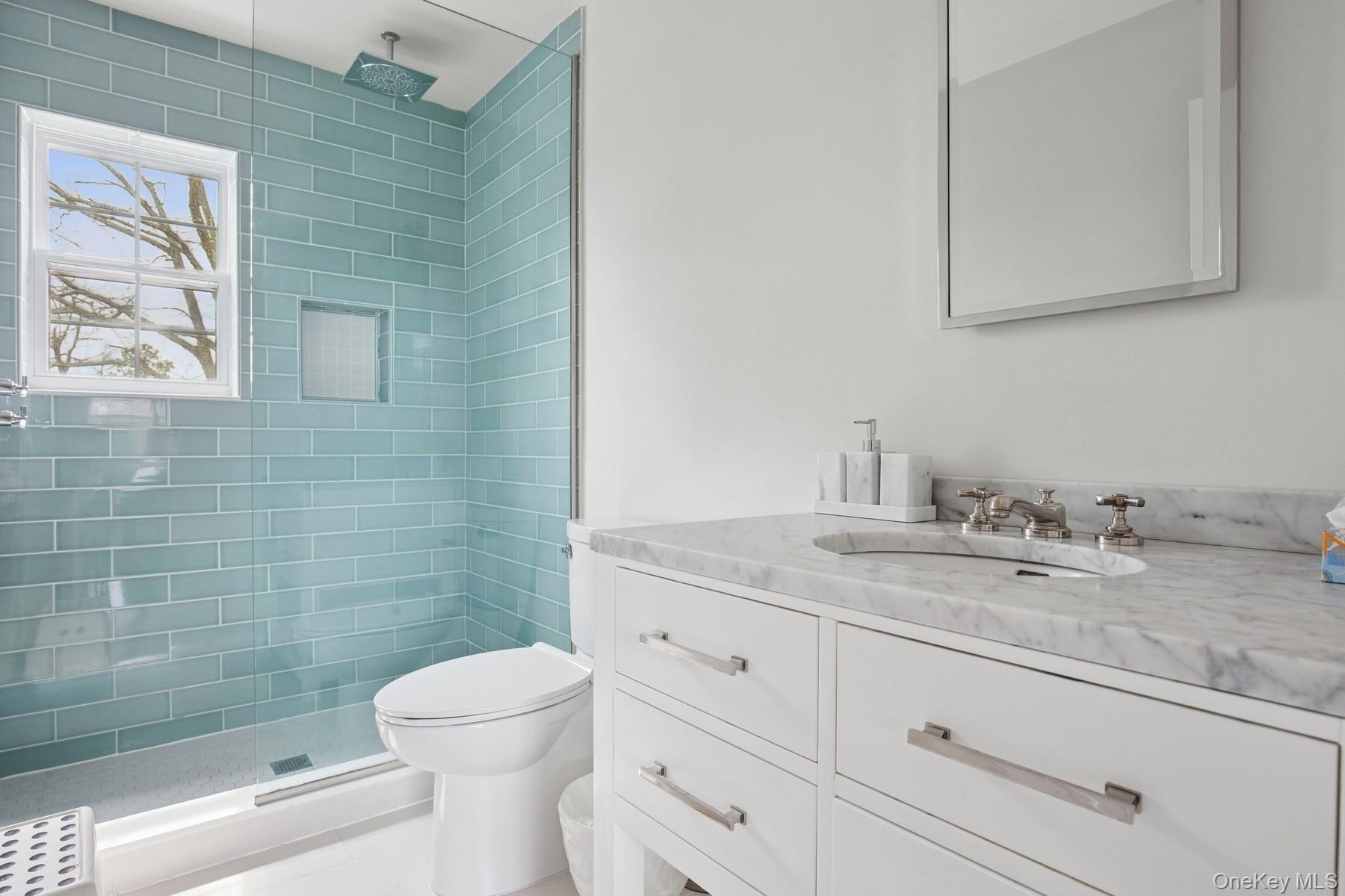 71 Old Canoe Place Road Hampton Bays, NY 11946 - Photo 25 of 34 a bathroom with a granite countertop toilet a sink a mirror and a shower