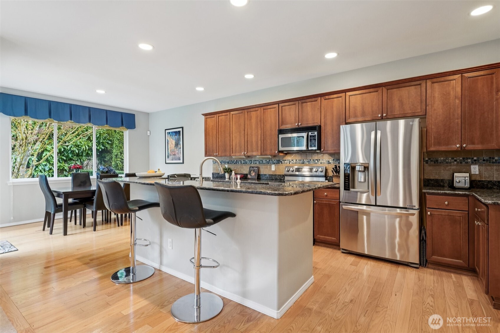 206 Pasco Drive Northeast Renton, WA 98059 - Photo 9 of 40 a kitchen with stainless steel appliances granite countertop a refrigerator a stove a sink a dining table and chairs with wooden floor