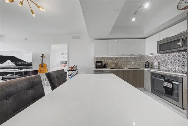 a large white kitchen with stainless steel appliances granite countertop a stove and a sink