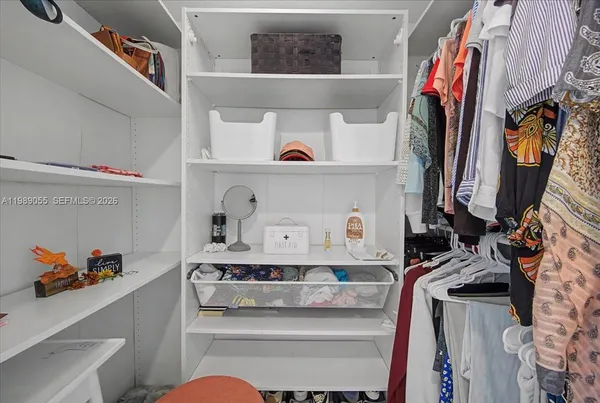 a view of walk in closet with clothes and shoes
