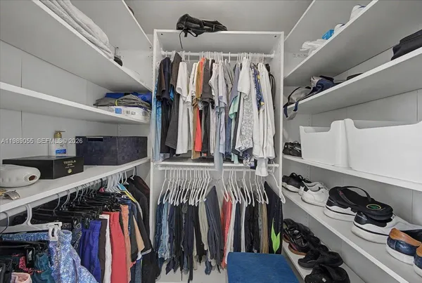a view of walk in closet with clothes and shoes