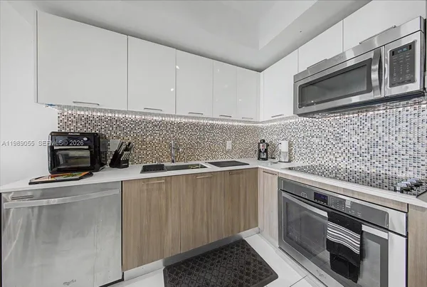 a kitchen with stainless steel appliances a sink a stove a microwave a sink a refrigerator and cabinets