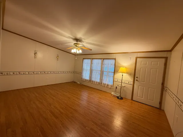 an empty room with wooden floor and chandelier