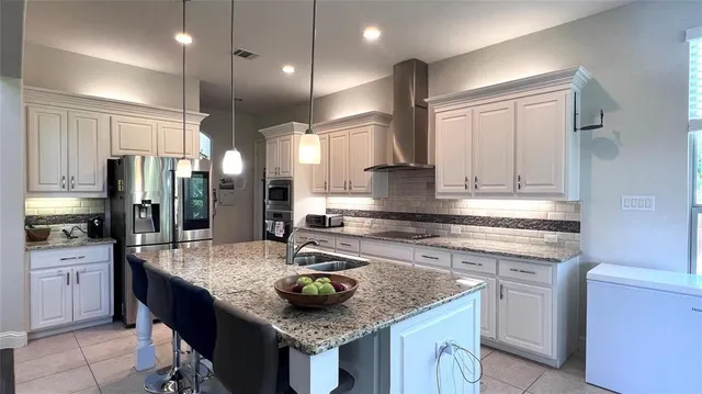 a kitchen with stainless steel appliances granite countertop a sink a stove and a refrigerator