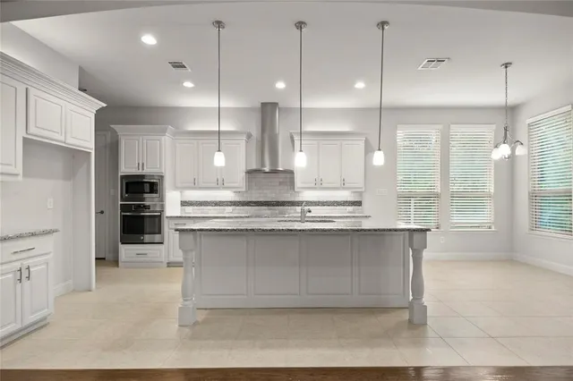 a large kitchen with kitchen island white cabinets and stainless steel appliances