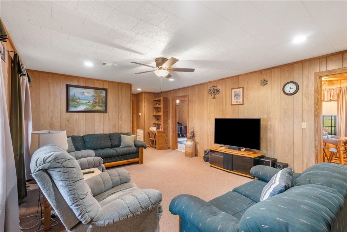 13339 Bj Dusek Road Wallis, TX 77485 - Photo 14 of 39 This cozy living room features wood-paneled walls, carpeted floors, and a ceiling fan. It includes comfortable seating, and ample natural light from a window. Ideal for relaxing and entertaining.
