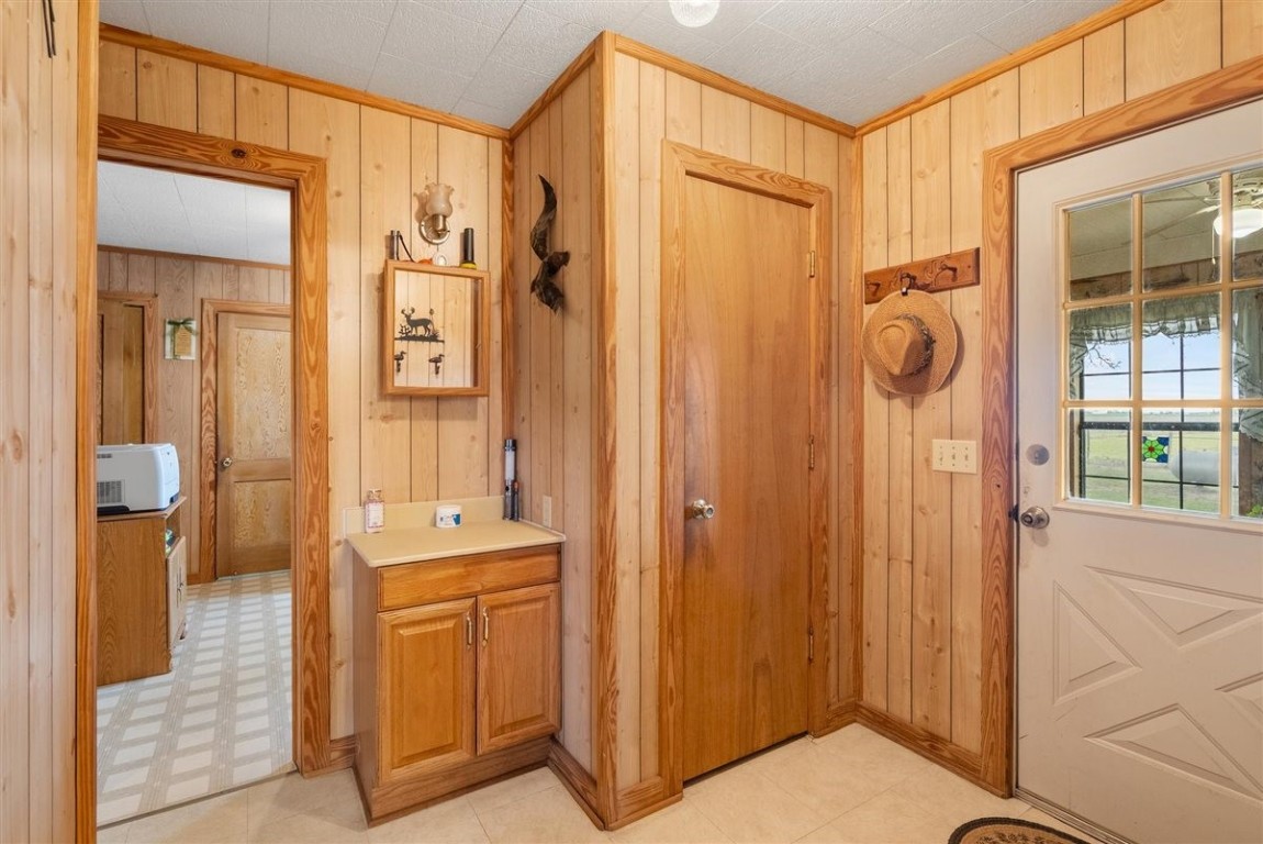 13339 Bj Dusek Road Wallis, TX 77485 - Photo 16 of 39 This cozy entryway features wood-paneled walls, a small counter with cabinet storage, and a door leading outside. The space is warm and inviting, with hooks for hanging hats or coats and a glimpse into an adjoining room with patterned flooring.