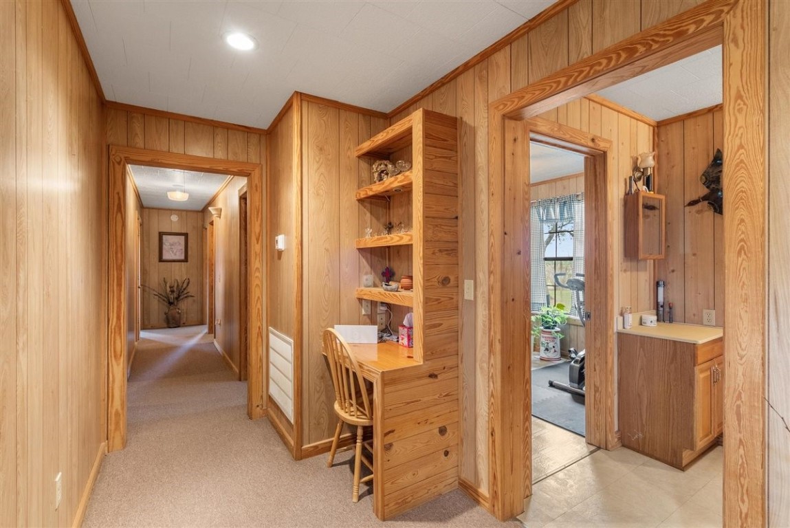 13339 Bj Dusek Road Wallis, TX 77485 - Photo 17 of 39 This hallway features warm wood paneling, a built-in desk, and leads to adjacent rooms including a cozy seating area and a room with potential for a home gym or sunroom.