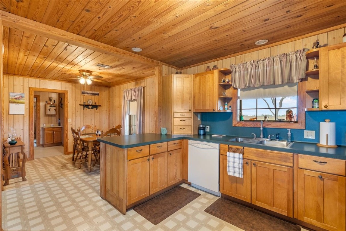 13339 Bj Dusek Road Wallis, TX 77485 - Photo 18 of 39 This cozy kitchen features warm wood paneling and cabinetry, a spacious layout with ample counter space, and a window above the sink offering a pleasant view. The adjacent dining area is well-lit and inviting, perfect for family meals.