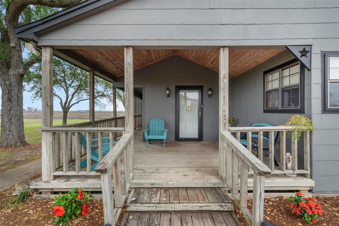 13339 Bj Dusek Road Wallis, TX 77485 - Photo 2 of 39 Charming rustic front porch with wooden railing and ceiling, it offers a cozy and inviting entrance to the home.