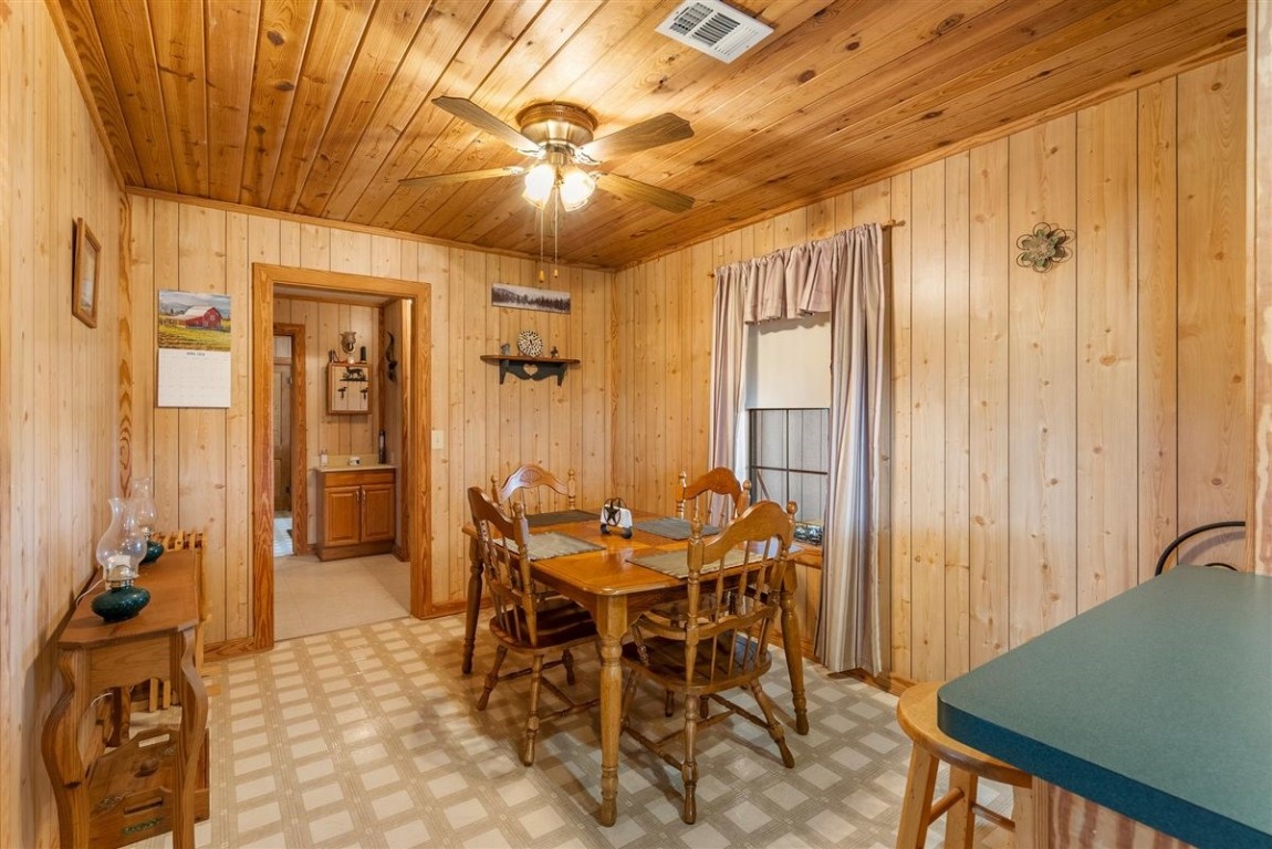 13339 Bj Dusek Road Wallis, TX 77485 - Photo 21 of 39 This cozy dining area features wood paneling on the walls and ceiling, creating a warm, rustic feel. It includes a ceiling fan and a window with curtains for natural light.