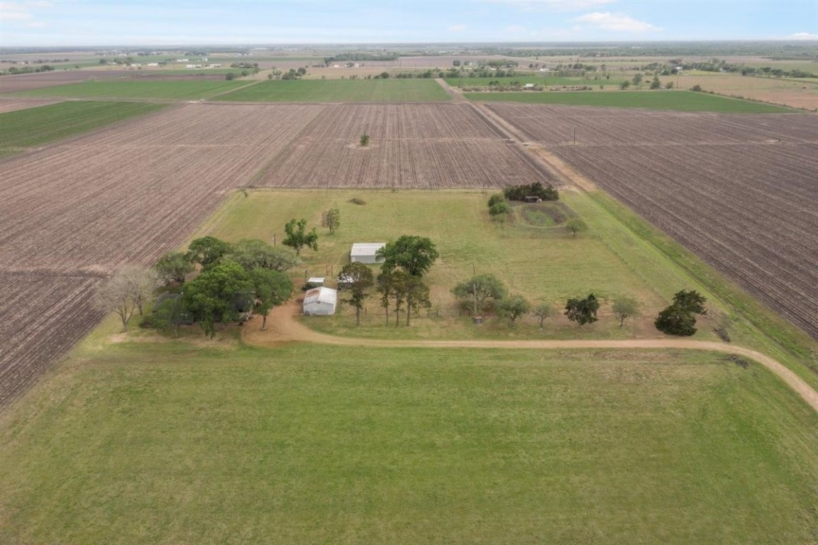 13339 Bj Dusek Road Wallis, TX 77485 - Photo 30 of 39 This aerial photo showcases a rural property surrounded by expansive farmland. It features a central cluster of trees and a few structures, likely providing plenty of space and privacy. Ideal for those seeking a peaceful country lifestyle.