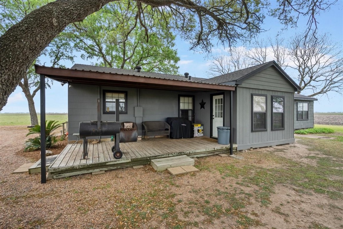 13339 Bj Dusek Road Wallis, TX 77485 - Photo 3 of 39 Back of the home with a cozy wooden porch, ideal for relaxing outdoors. Surrounded by open landscapes.