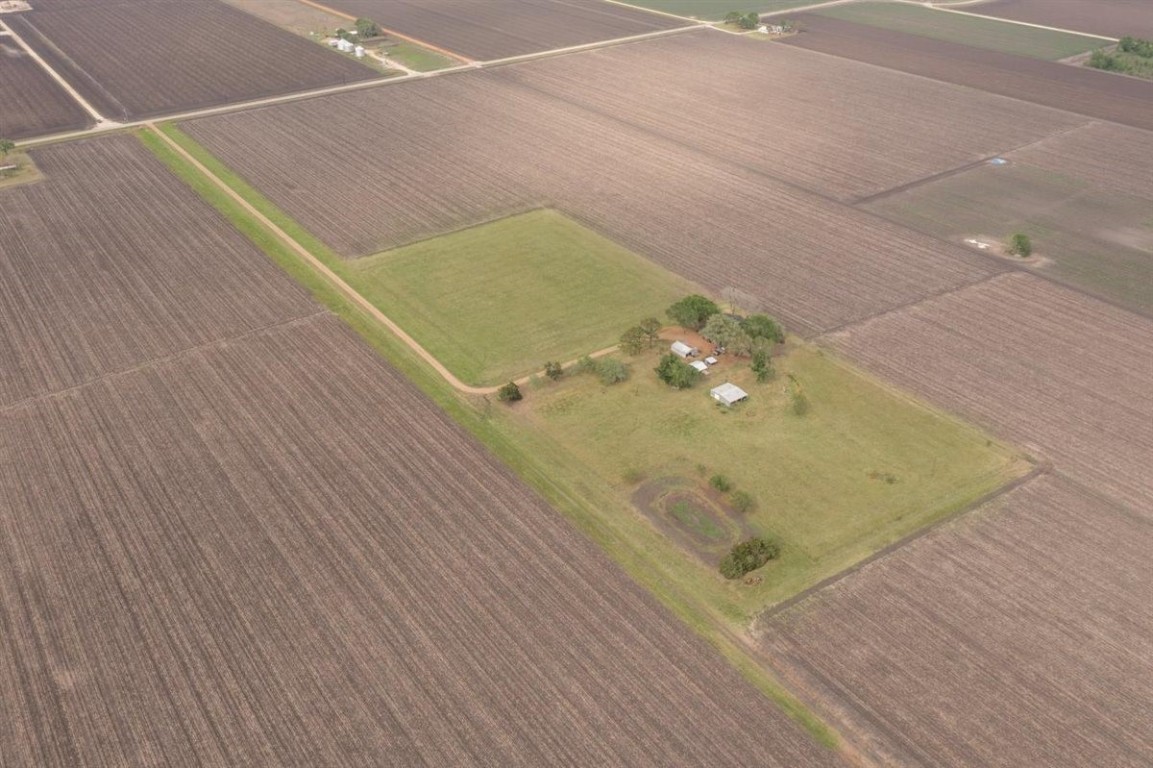13339 Bj Dusek Road Wallis, TX 77485 - Photo 34 of 39 This aerial photo showcases a rural property surrounded by expansive fields. The central area features a few structures and trees, offering a secluded, spacious living environment. Ideal for those seeking privacy and a connection with nature.