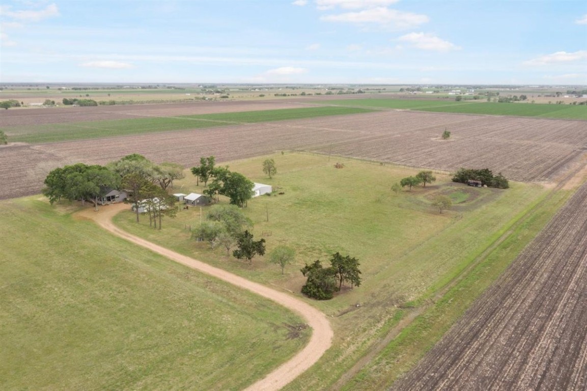 13339 Bj Dusek Road Wallis, TX 77485 - Photo 35 of 39 Expansive rural property featuring a central home surrounded by trees, nestled in open fields. Ideal for privacy and agricultural opportunities, with a long driveway leading to the house.