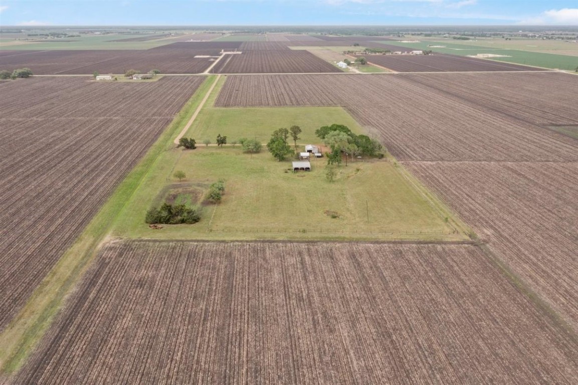 13339 Bj Dusek Road Wallis, TX 77485 - Photo 36 of 39 Aerial view of a rural property featuring a central cluster of trees and a small building, surrounded by expansive farmland. Ideal for those seeking privacy and open space.
