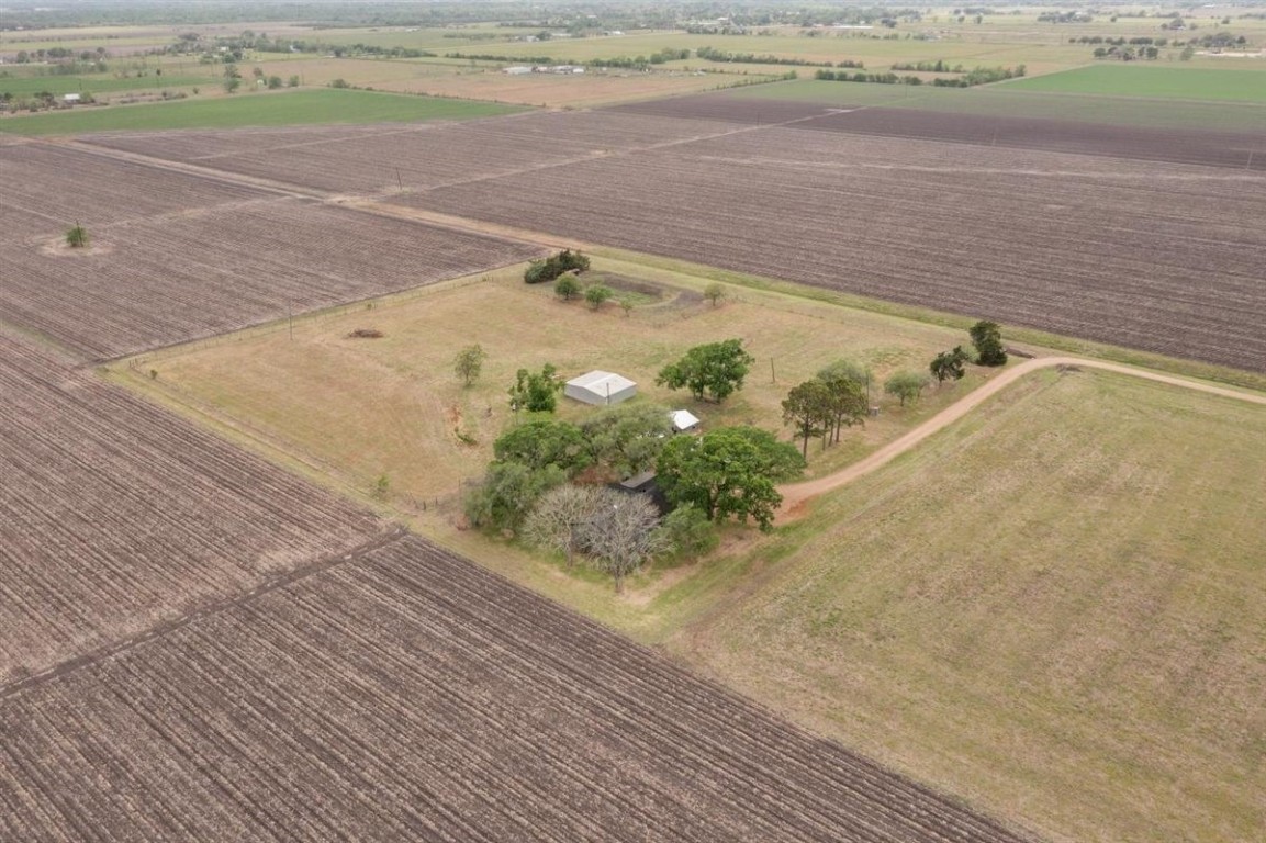 13339 Bj Dusek Road Wallis, TX 77485 - Photo 37 of 39 Aerial view of a rural property surrounded by expansive farmland. Features a small house and several trees, offering privacy and open space. Ideal for those seeking a secluded, agricultural setting.