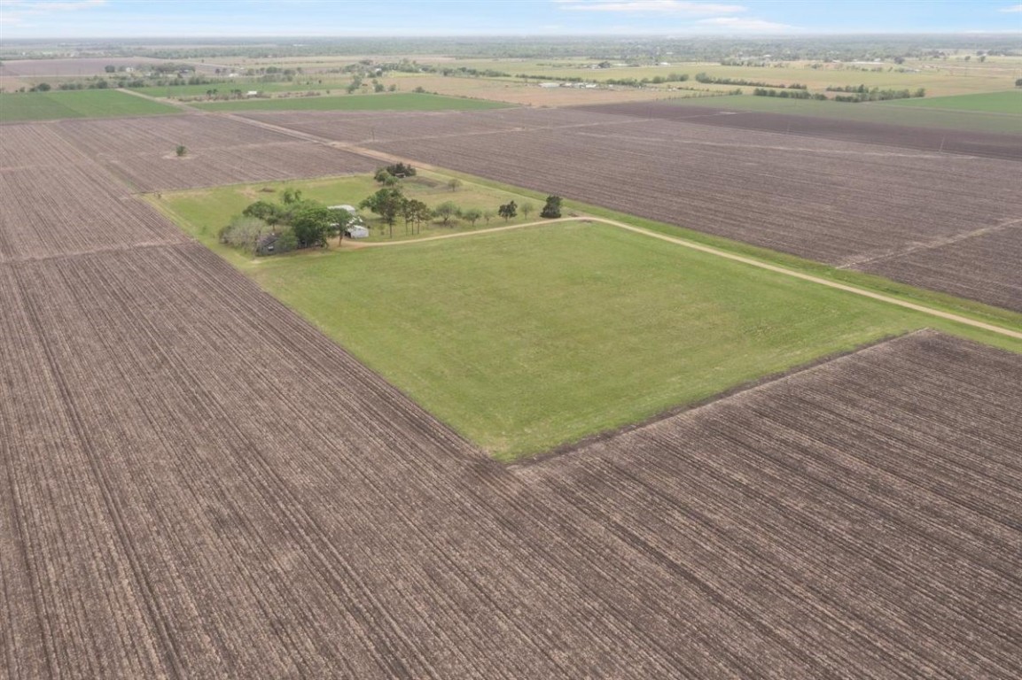 13339 Bj Dusek Road Wallis, TX 77485 - Photo 38 of 39 Expansive aerial view of a rural property featuring a house surrounded by trees, set within vast, cultivated fields. Ideal for those seeking tranquility and open space.