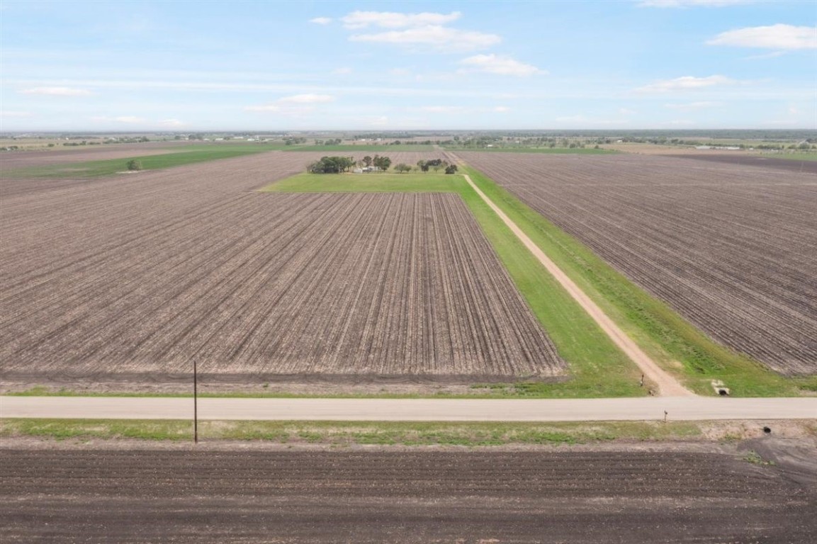 13339 Bj Dusek Road Wallis, TX 77485 - Photo 39 of 39 Expansive rural farmland with neatly plowed fields, a long dirt road leading to a cluster of trees, and a distant view of open skies. Ideal for agriculture or a peaceful country retreat.