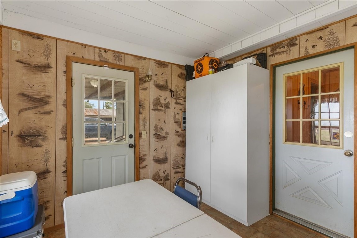 13339 Bj Dusek Road Wallis, TX 77485 - Photo 8 of 39 This room features wood paneling with nature-themed wallpaper, two doors with windows, a white storage cabinet, offering a rustic, functional space.