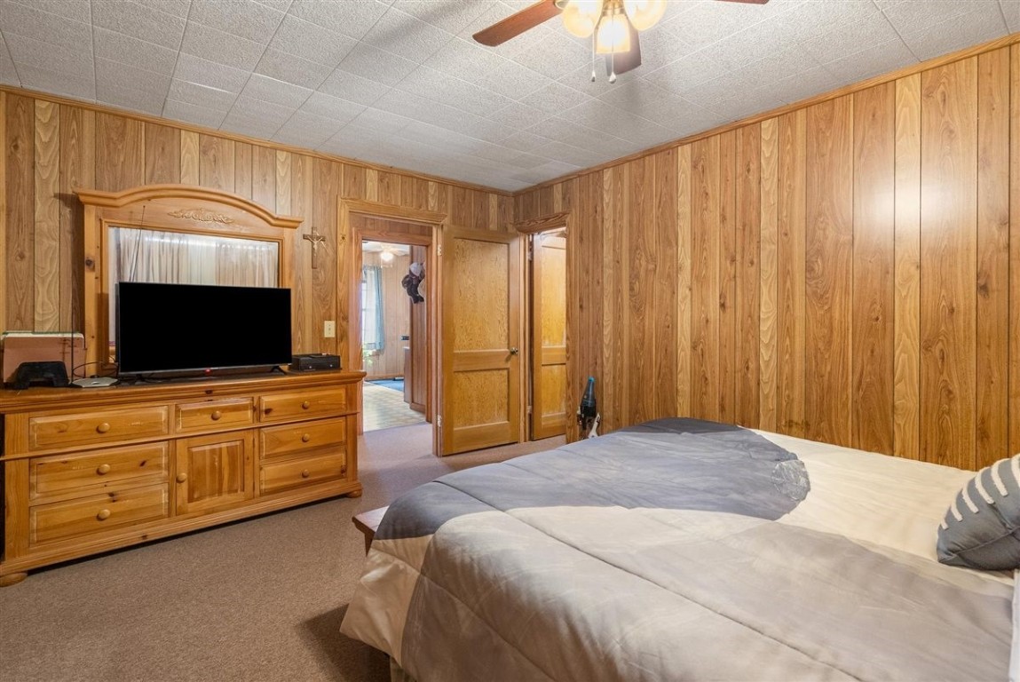 13339 Bj Dusek Road Wallis, TX 77485 - Photo 10 of 39 Cozy bedroom with wood-paneled walls, carpeted flooring, and a ceiling fan.
