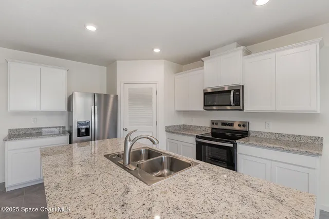 a kitchen with granite countertop a sink stainless steel appliances and white cabinets