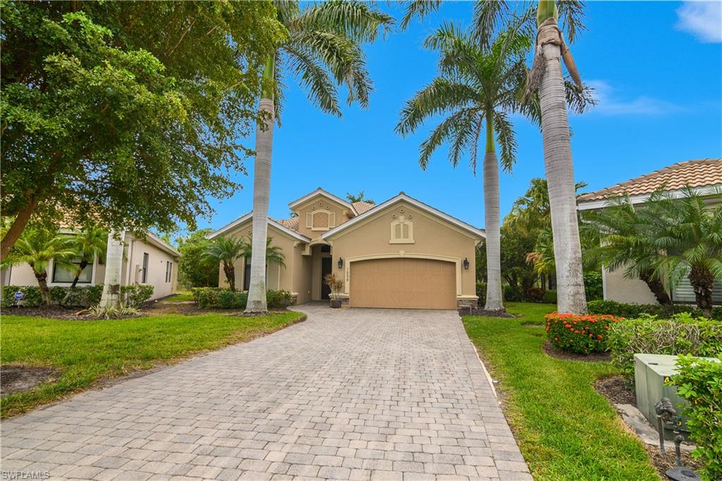 Mediterranean / spanish house with stucco siding, decorative driveway, an attached garage, and a front yard