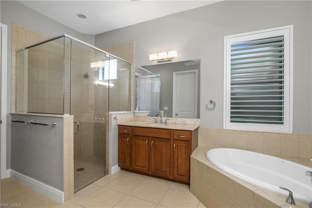 1558 Serrano Circle Naples, FL 34105 - Photo 15 of 31 a bathroom with a double vanity sink toilet mirror and bathtub