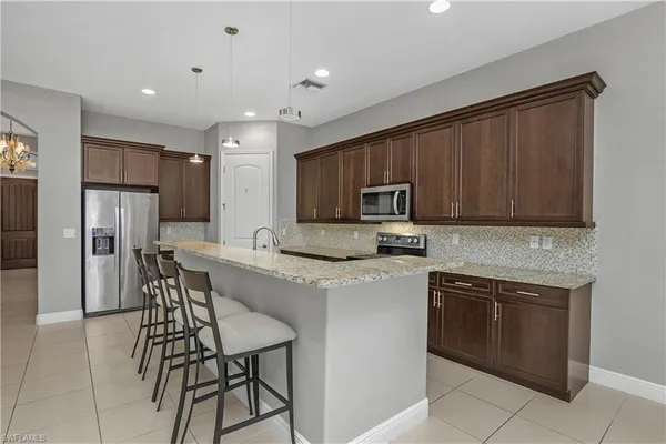 a kitchen with stainless steel appliances granite countertop a stove top oven a refrigerator a sink and a microwave