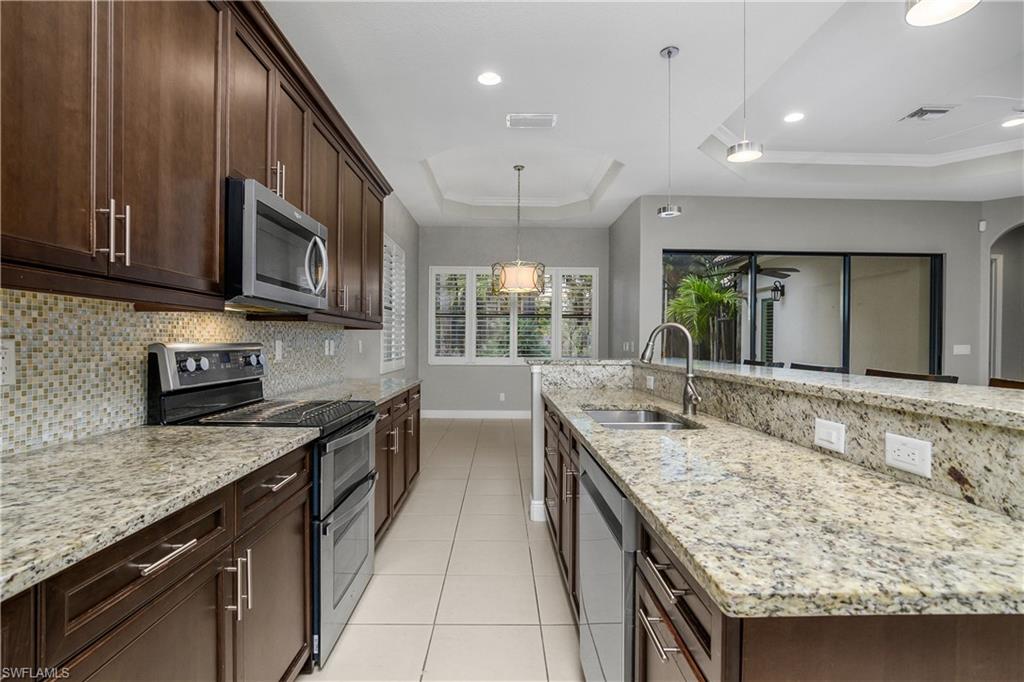 1558 Serrano Circle Naples, FL 34105 - Photo 8 of 31 a kitchen with stainless steel appliances granite countertop a sink stove and cabinets