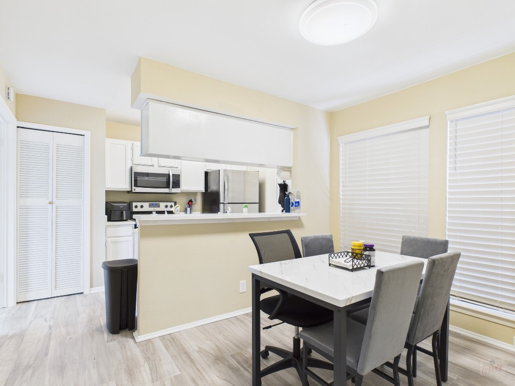3115 Helms Street, Unit 202 Austin, TX 78705 - Photo 16 of 26 a kitchen with stainless steel appliances a dining table chairs and wooden floor