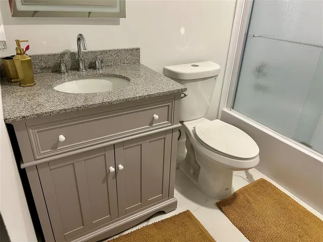 a bathroom with a granite countertop sink toilet and shower