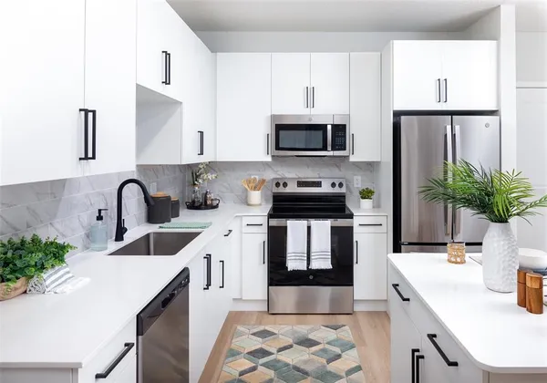 a kitchen with stainless steel appliances a sink a stove a microwave a sink a refrigerator and cabinets