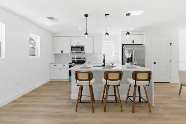 a kitchen with stainless steel appliances kitchen island granite countertop a table chairs sink and cabinets