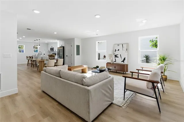 a living room with furniture and a dining table with wooden floor