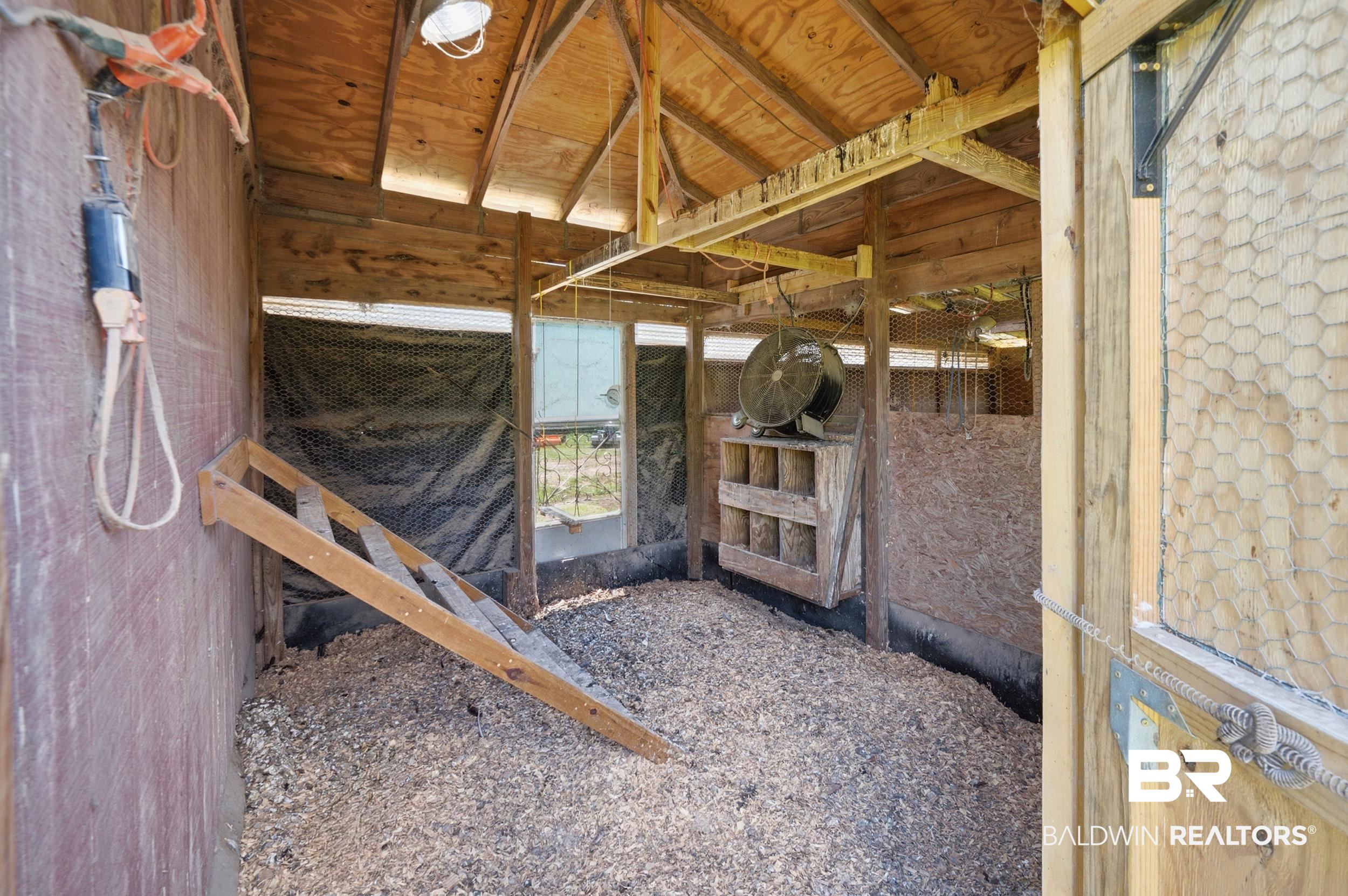15855 Calvin Richerson Road Bay Minette, AL 36507 - Photo 71 of 83 Interior outbuilding featuring a sloped wooden ramp, integrated nesting boxes, and a wood chip floor