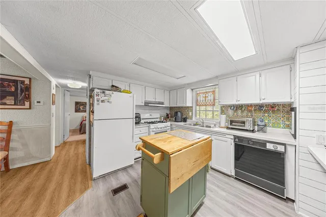 a kitchen with granite countertop a refrigerator and a stove top oven