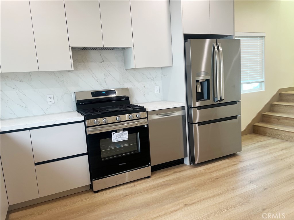 1514 East Woodbury Road, Unit 1/2 Pasadena, CA 91104 - Photo 4 of 14 a kitchen with granite countertop wooden floors and stainless steel appliances