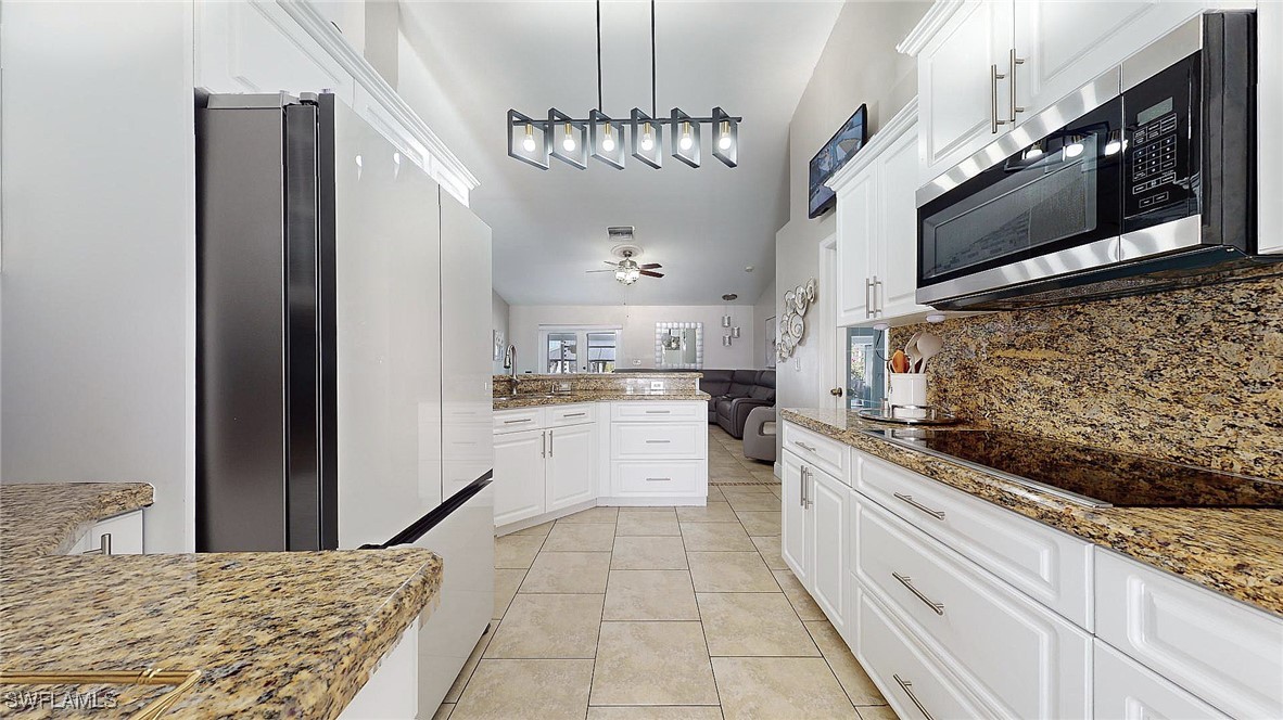 2602 5th Street Southwest Lehigh Acres, FL 33976 - Photo 5 of 17 a kitchen with stainless steel appliances kitchen island granite countertop a stove top oven a sink a counter space and cabinets