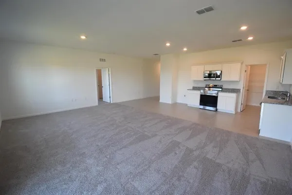 a view of a kitchen with kitchen island a sink wooden floor and black appliances