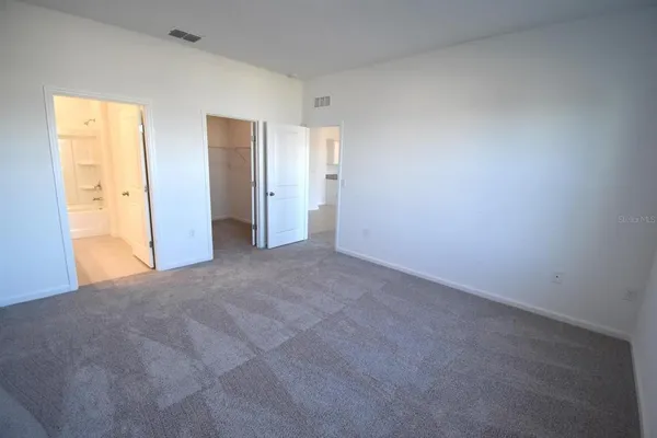 a view of an empty room with wooden floor and windows