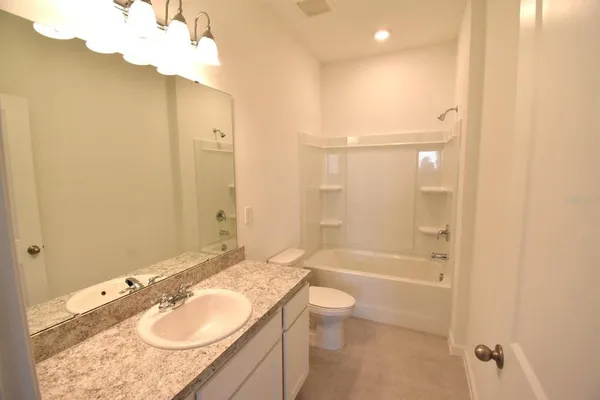 a bathroom with a granite countertop sink a toilet a mirror and shower