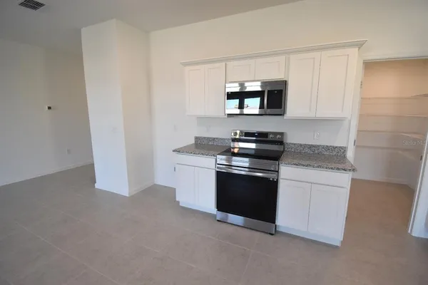 a kitchen with granite countertop white cabinets and stainless steel appliances