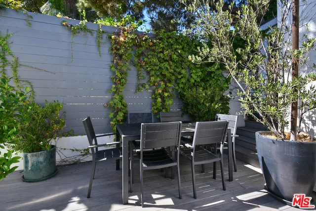 a view of a patio with table and chairs potted plants and large tree