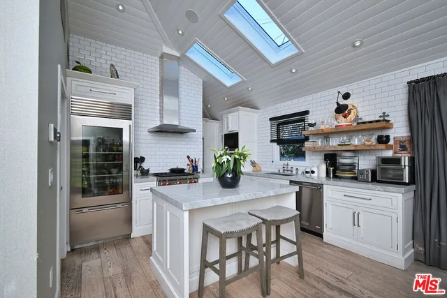 a kitchen with stainless steel appliances granite countertop a stove a sink dishwasher and a refrigerator with wooden floor