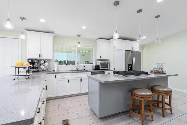 a kitchen with stainless steel appliances a dining table chairs sink and cabinets