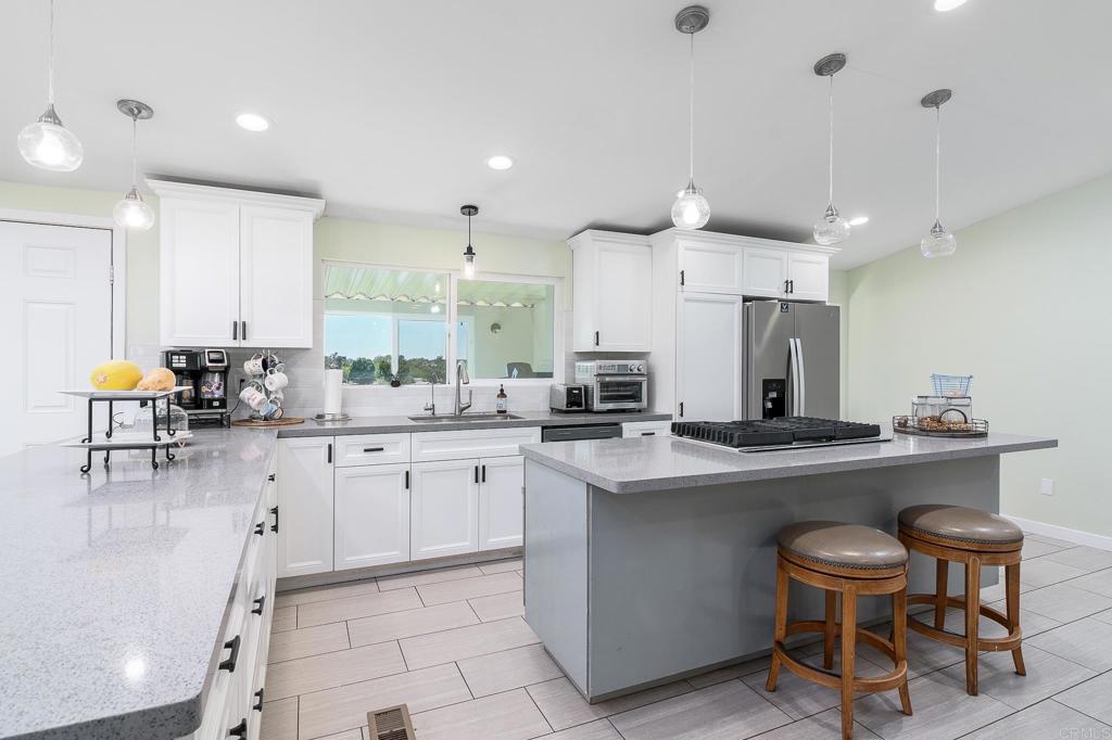 a kitchen with stainless steel appliances a dining table chairs sink and cabinets