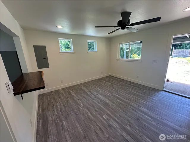 a view of an empty room with a window and wooden floor