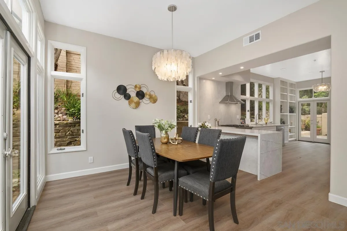 9605 Claiborne Square La Jolla, CA 92037 - Photo 17 of 34 a dining room with furniture a chandelier and wooden floor