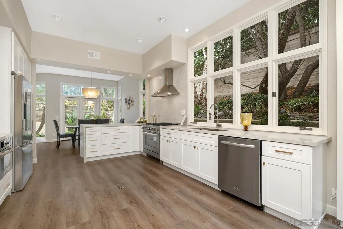 9605 Claiborne Square La Jolla, CA 92037 - Photo 19 of 34 a large white kitchen with granite countertop a large window and white appliances